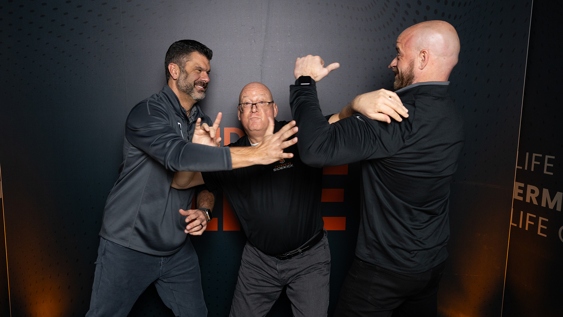 A photo of Ryan and Tyler fake fighting with Sidekick Advisor Tim in the middle
