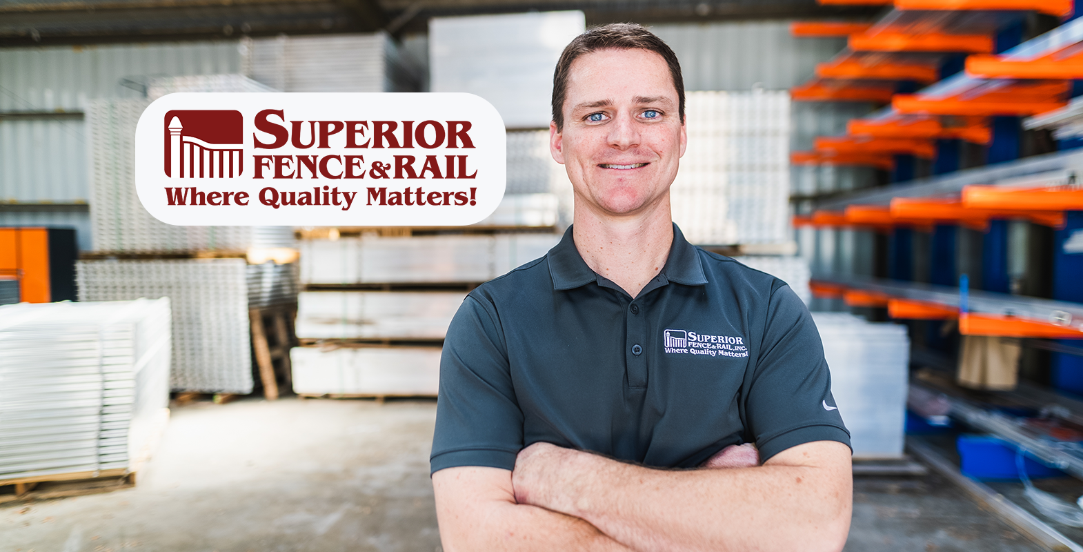 A man standing in a warehouse with his arms crossed smiling